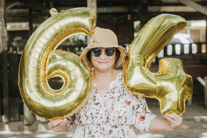 Picture of a senior woman holding balloons shaped 6 and 4